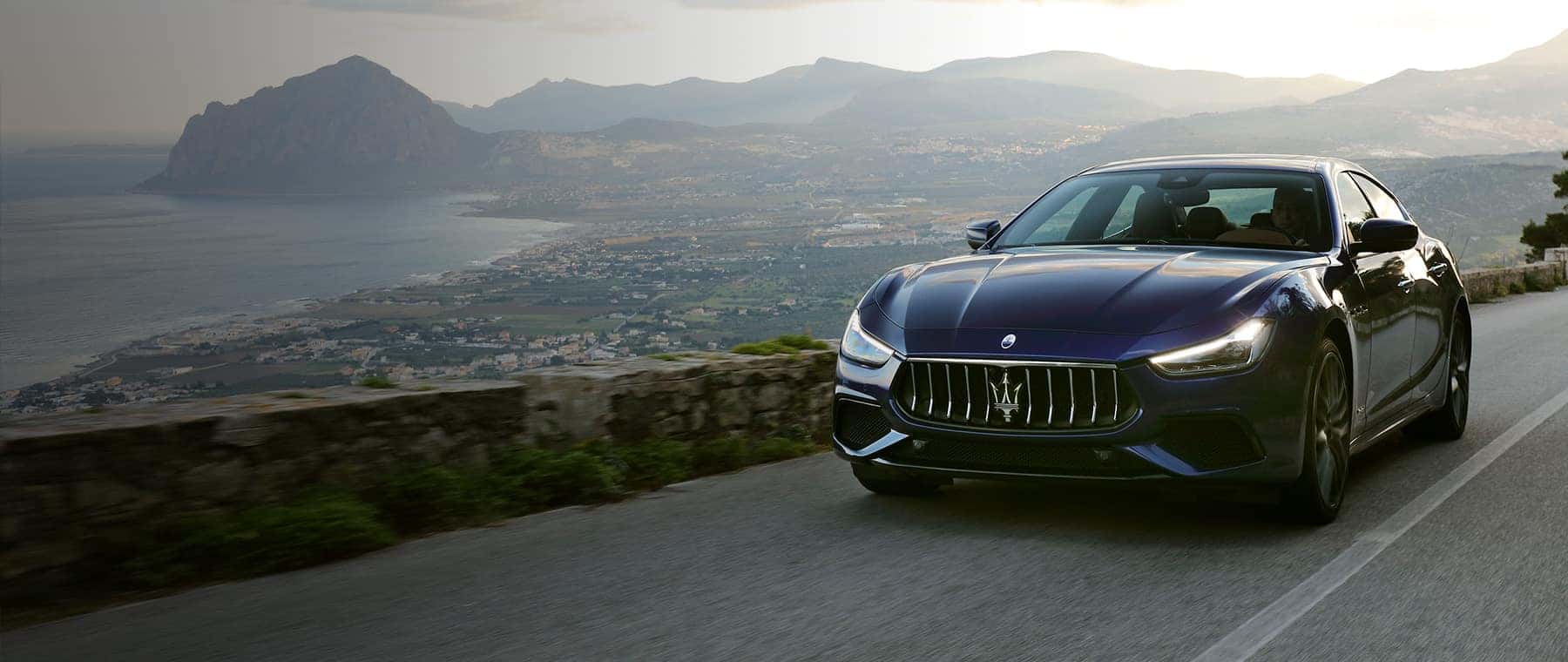 Maserati driving down a curving road in the mountains 