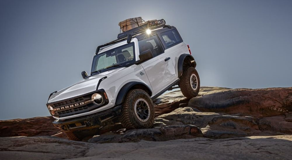 A white 2024 Ford Bronco Outer Banks is shown crawling over rocks after leaving a Ford dealer.