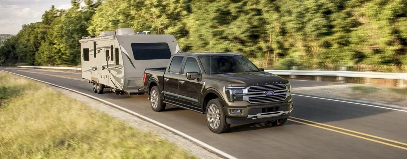 A black 2023 Ford F-150 Limited is shown towing a trailer.