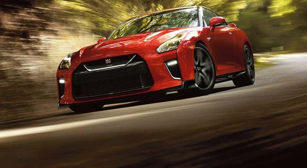 A red 2021 Nissan GT-R is driving on a track past blurred trees.