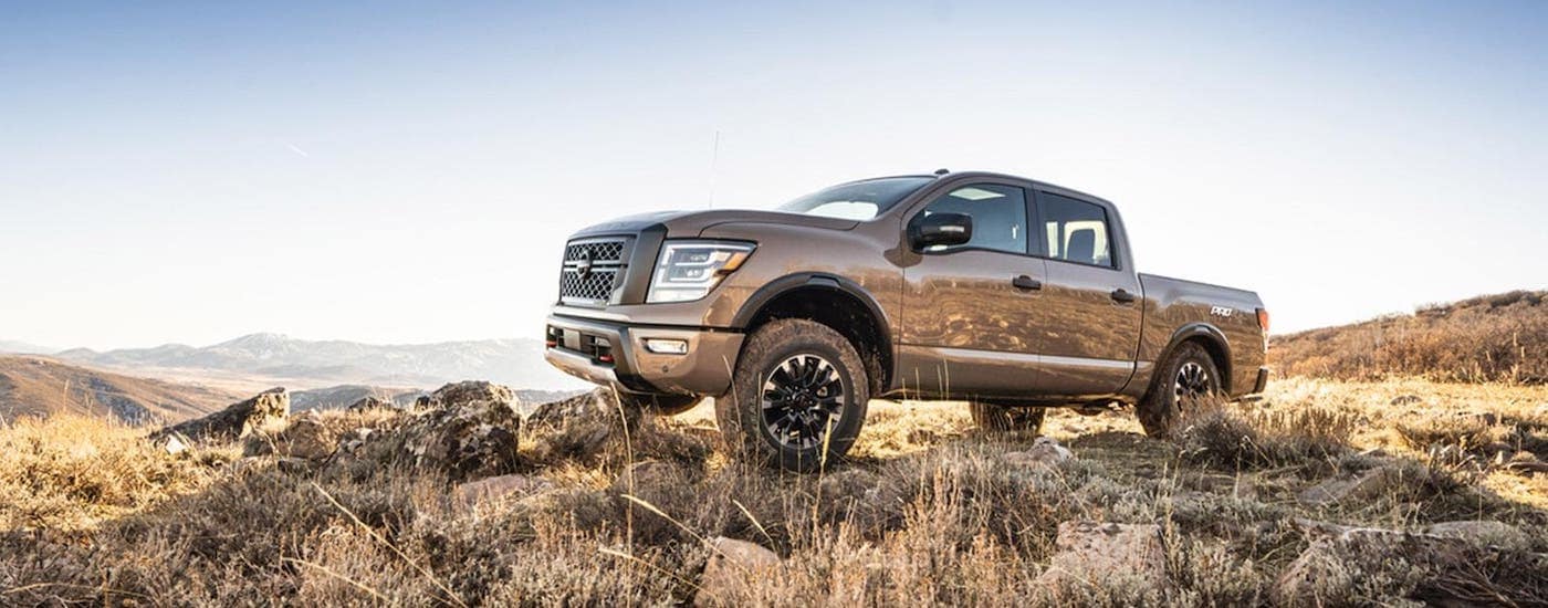 A brown 2020 Nissan Titan is climbing over rocks on a mountain after leaving a Nissan dealer near you.