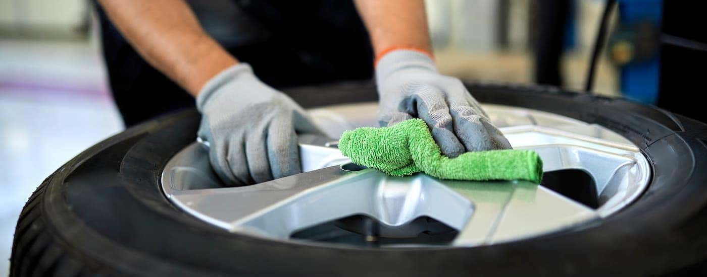 A closeup shows gloved hands cleaning the rims of a tire inside a local tire shop.