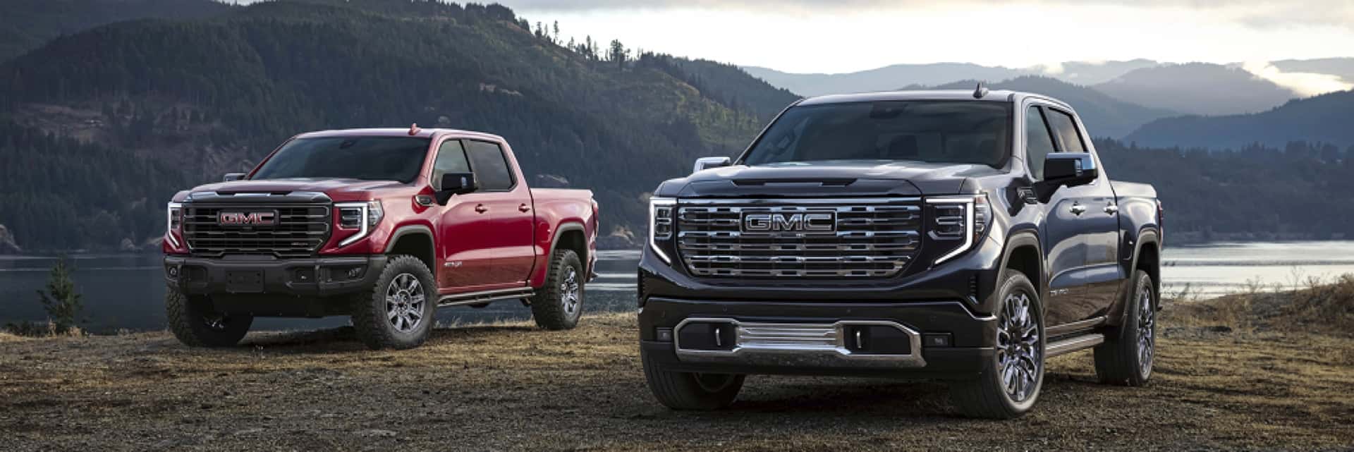 GMC-trucks-in-front-of-lake-surrounded-by-wooded-hills