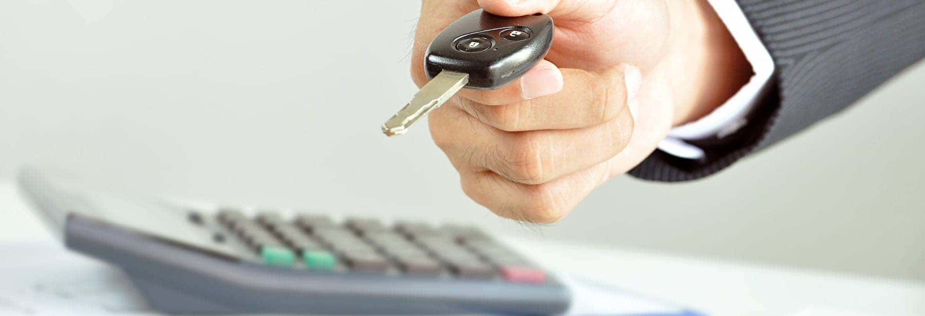 man holding key next to calculator