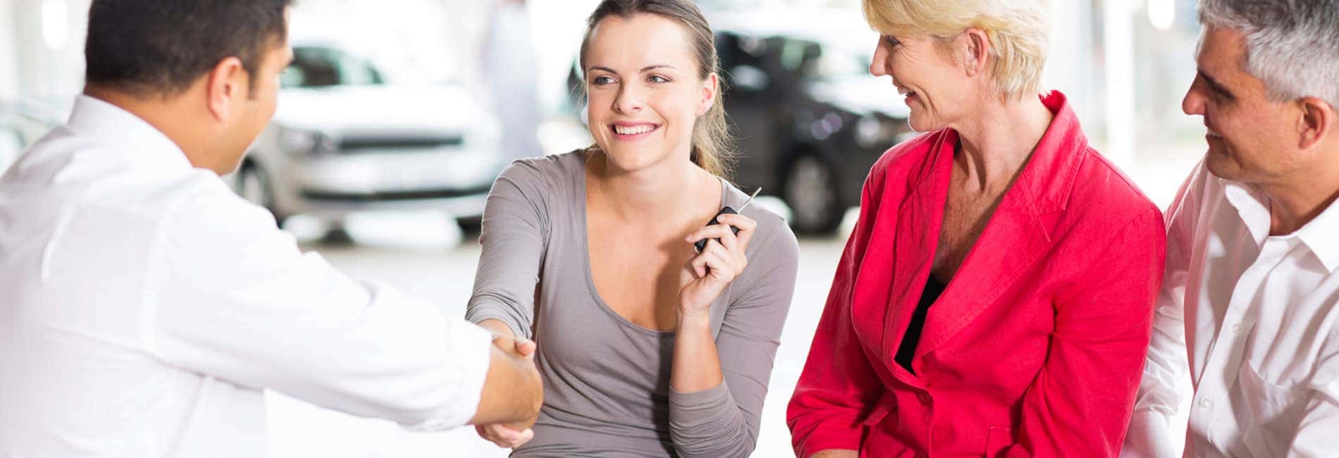 smiling woman with her family shaking a dealer_s hand