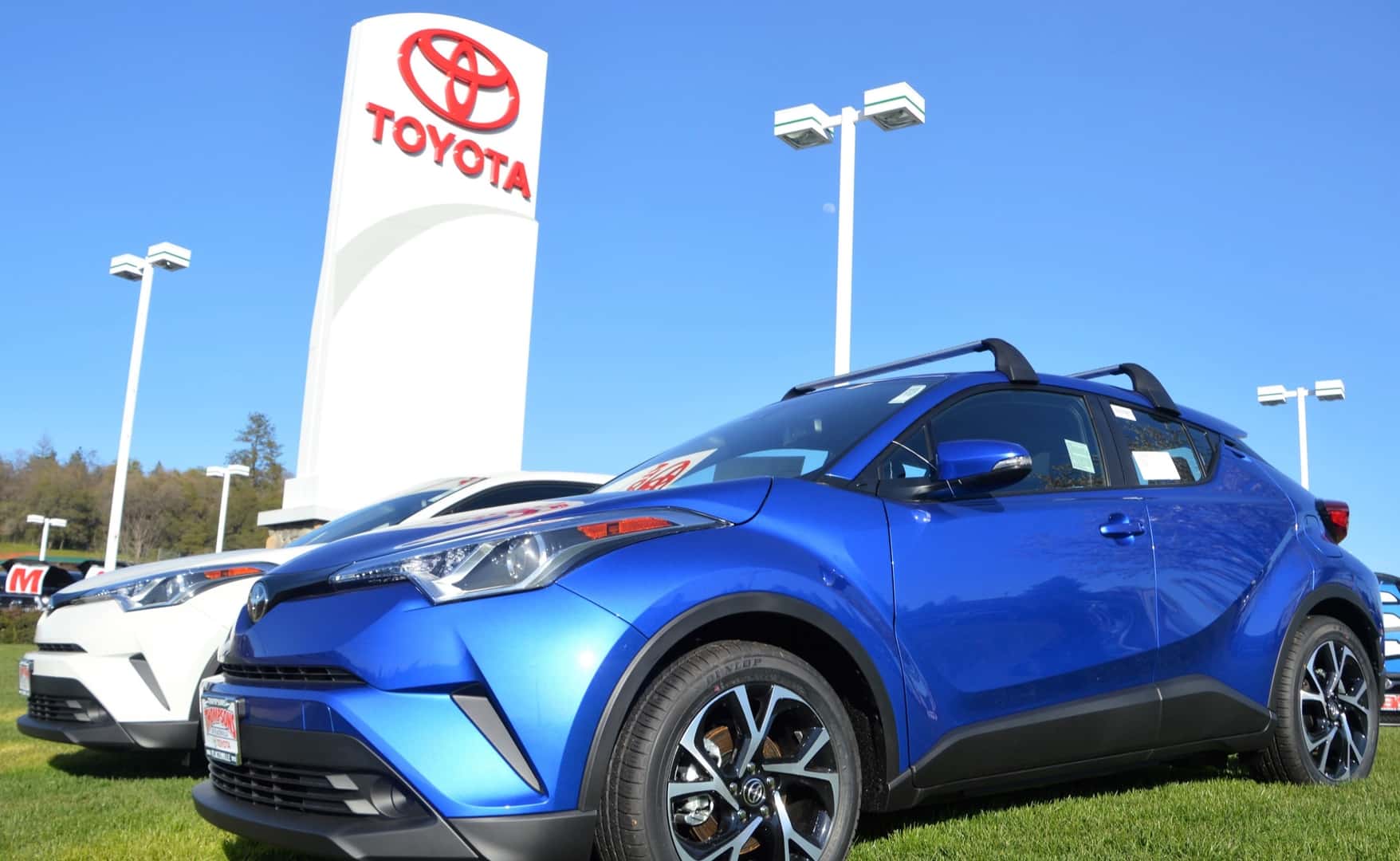 New Toyota parked on grass by Toyota sign
