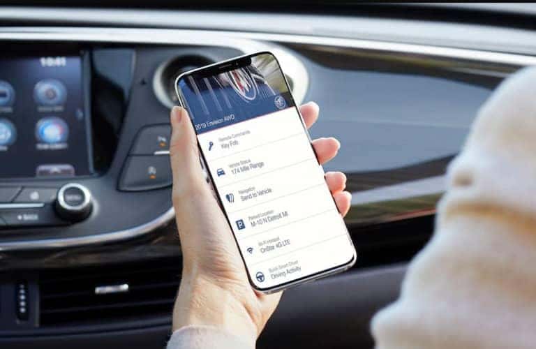 person_holding_phone_with_Buick_Connected_Services_app_in_car_o