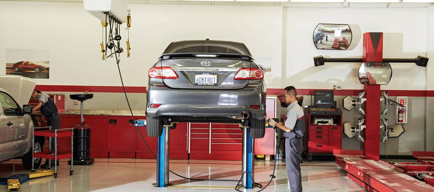 Toyota Service Center and a technician is working on a raised car