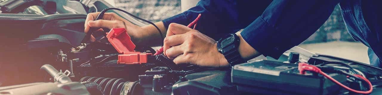 Close up view of a service tech testing a car battery