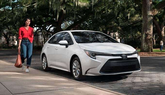person walking next to white corolla