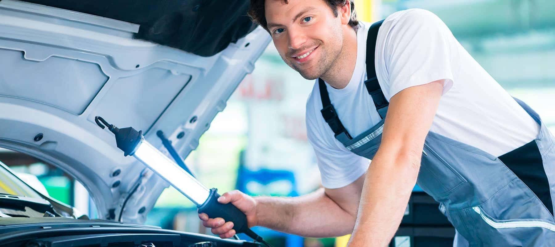 mechanic under the hood of a car smiling at you