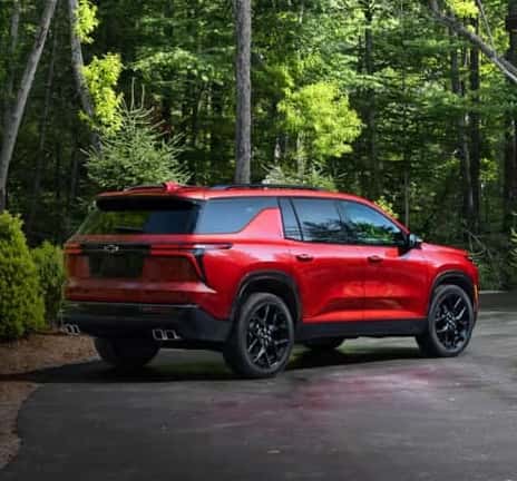 Red Chevrolet parked in a driveway in the woods