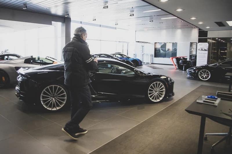 dealership showroom with a man taking pictures of a vehicle on his mobile