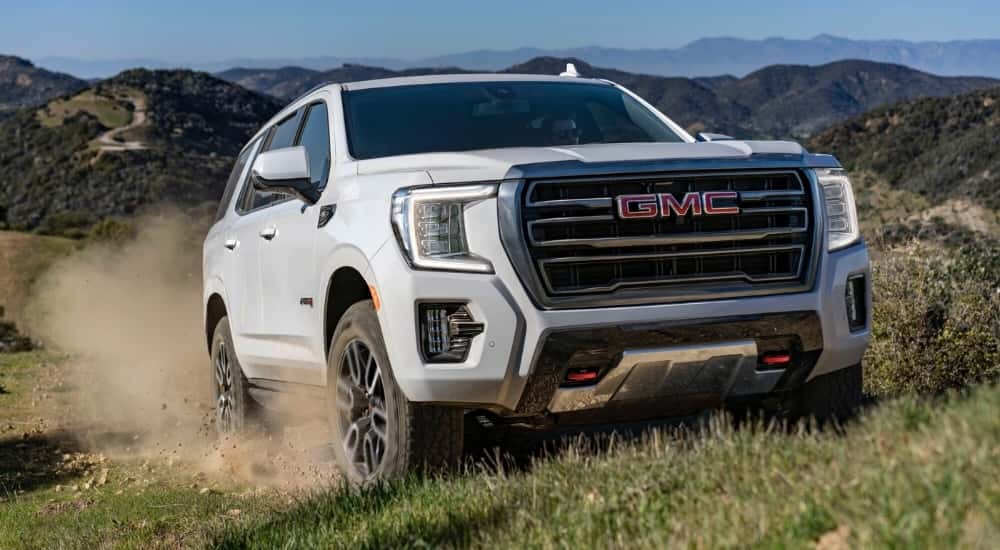 White 2022 GMC Yukon AT4 driving to a used GMC dealer