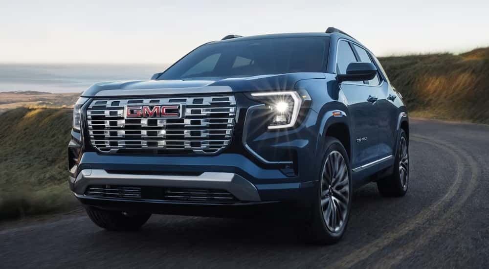 A blue 2026 GMC Terrain Denali driving down a road