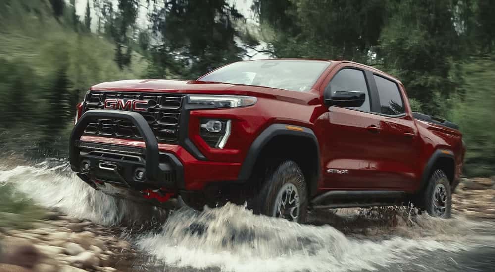 Red 2026 GMC Canyon AT4X driving through a creek
