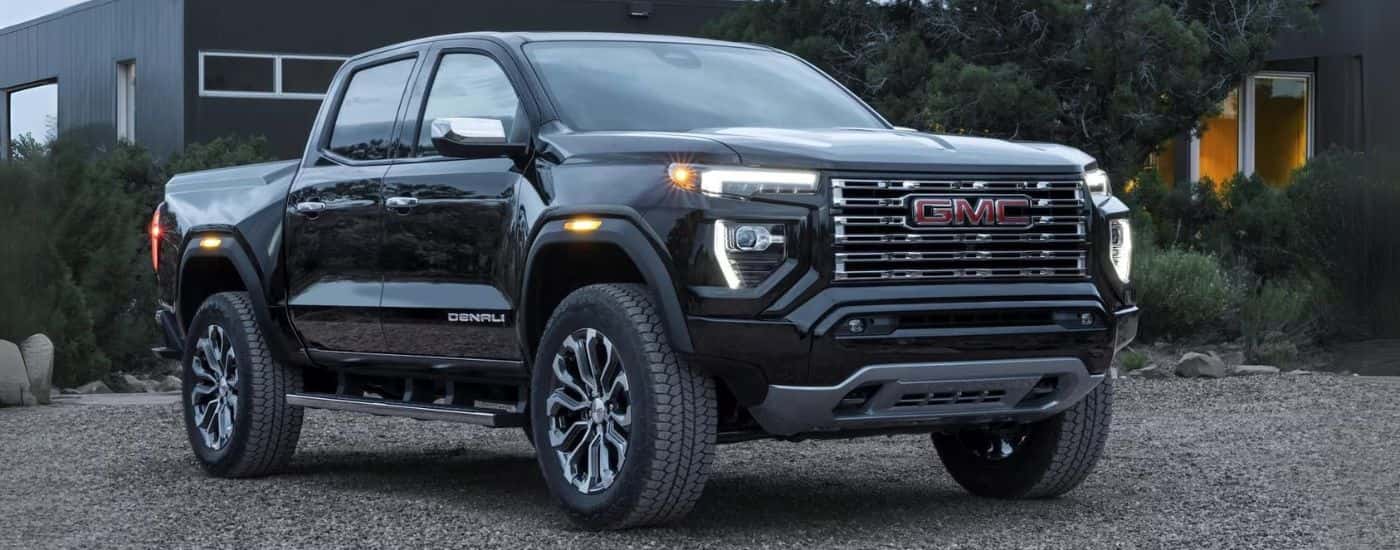 Black 2023 GMC Canyon Denali parked near a house.