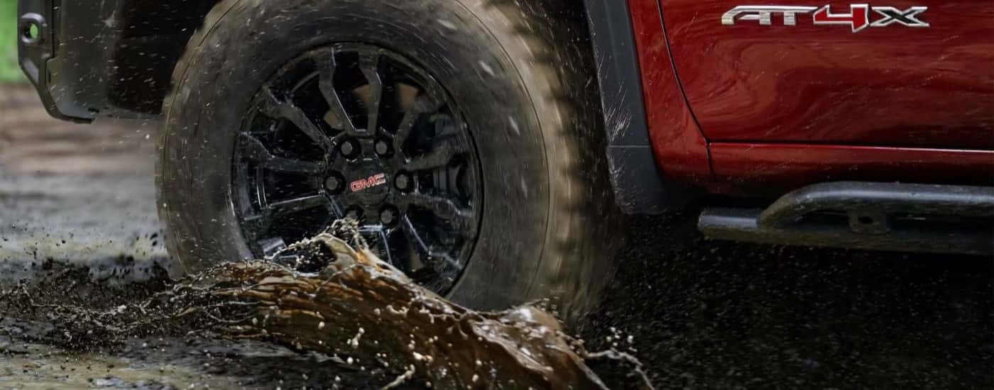Close-up f a red 2023 GMC Sierra 1500 AT4X driving through mud