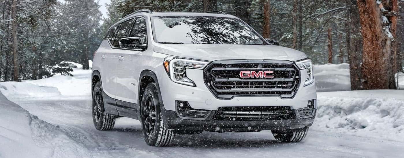 White 2024 GMC Terrain AT4  driving on a snowy trail