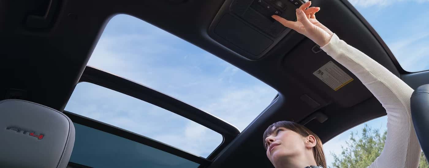 Person opening the moonroof in a 2026 GMC Acadia for sale