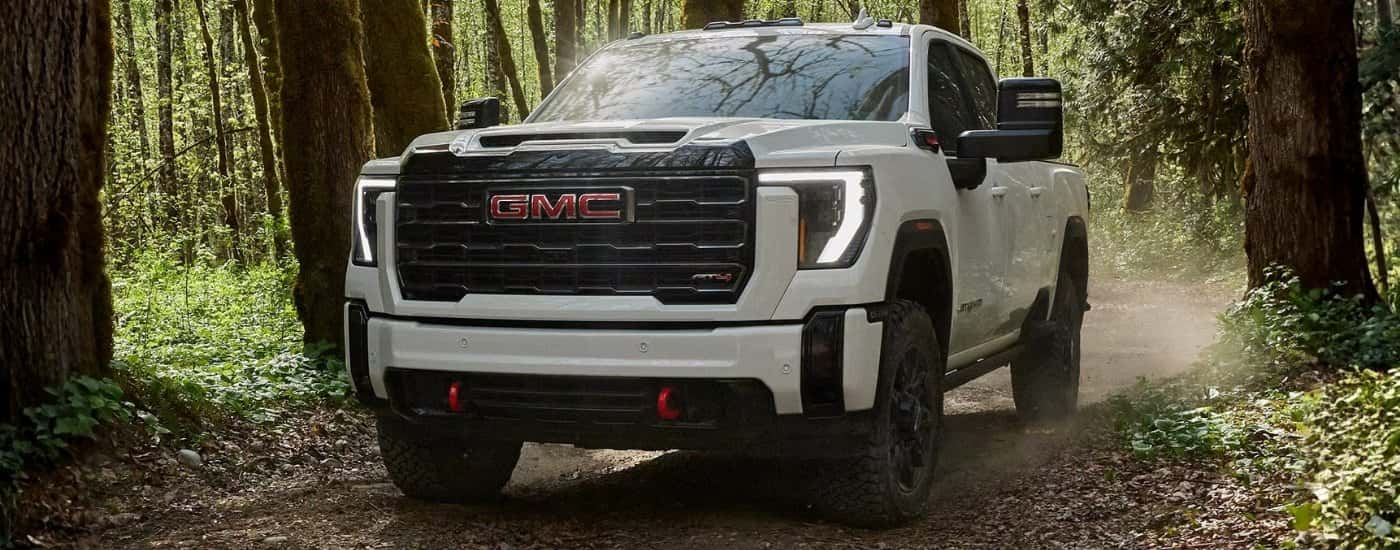 White 2026 GMC Sierra 2500 HD AT4 driving on a trail