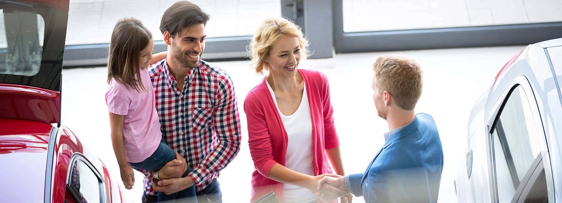 young-family-in-car-dealership-showroom-with-sales-team-member