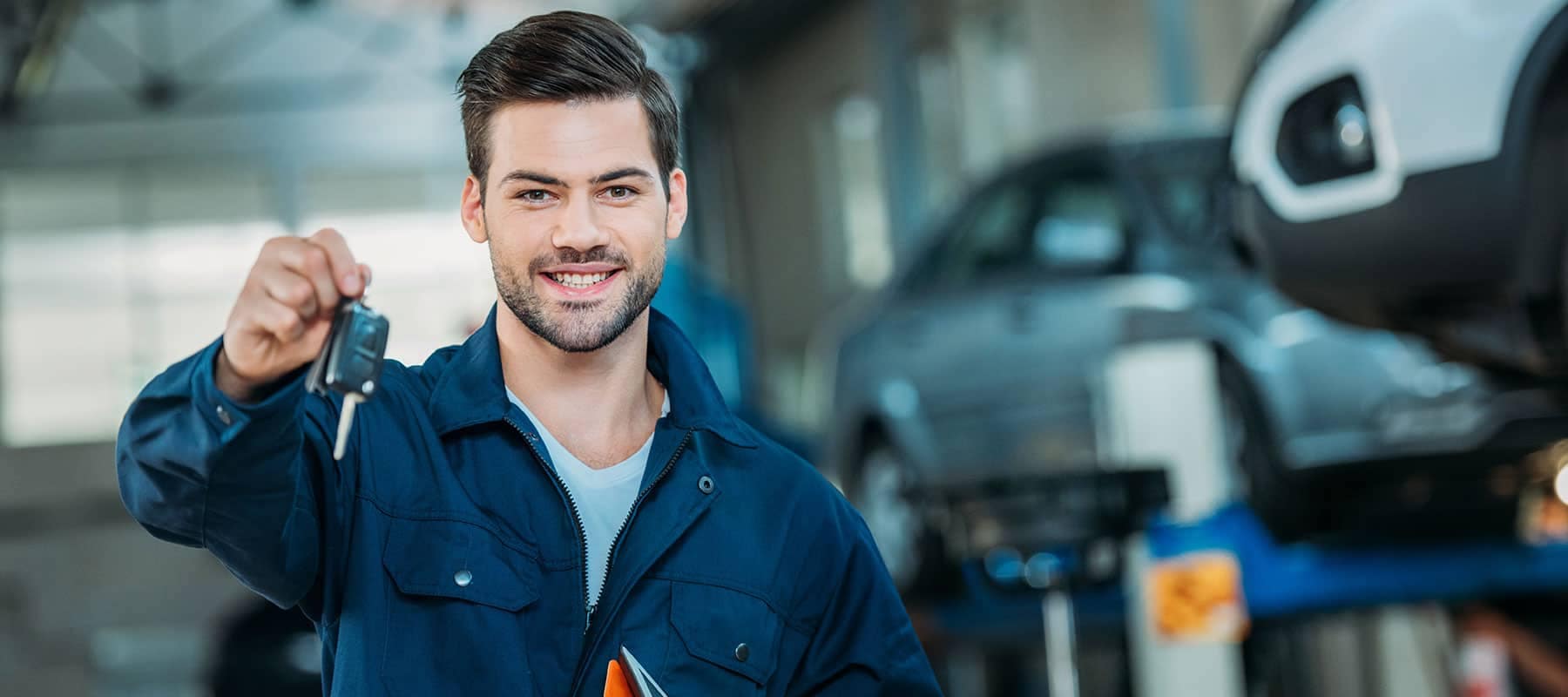 Service picture of technician holding car keys out and smiling