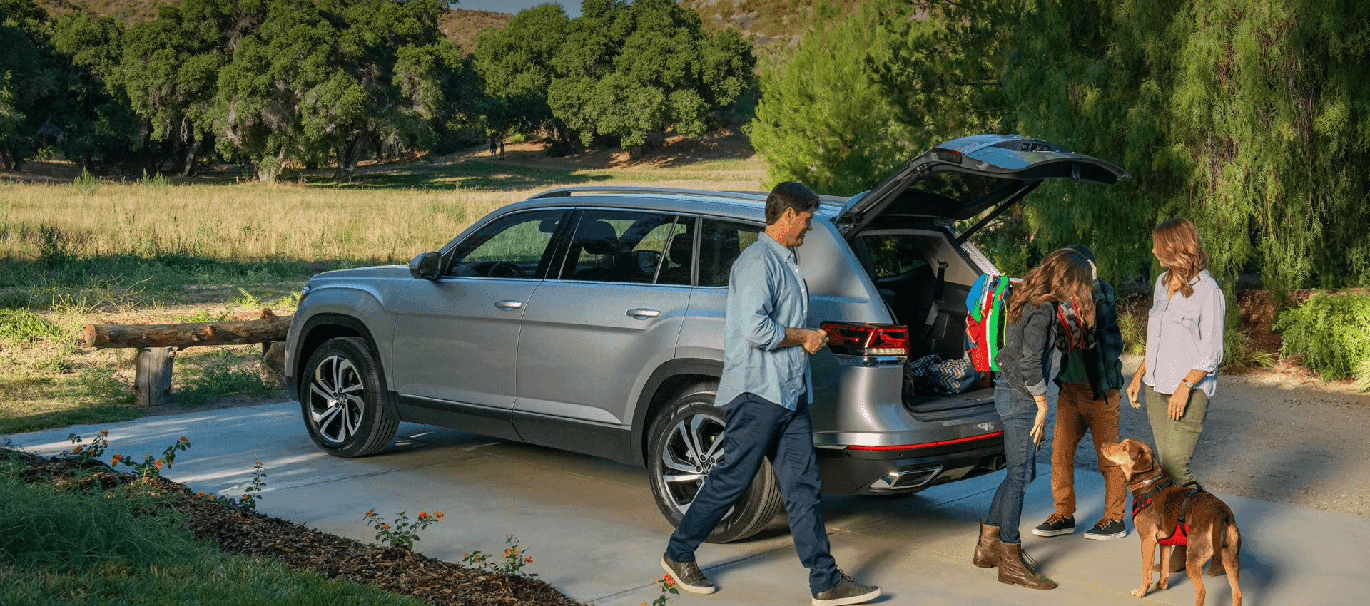Family and dog at the tailgate of a VW SUV