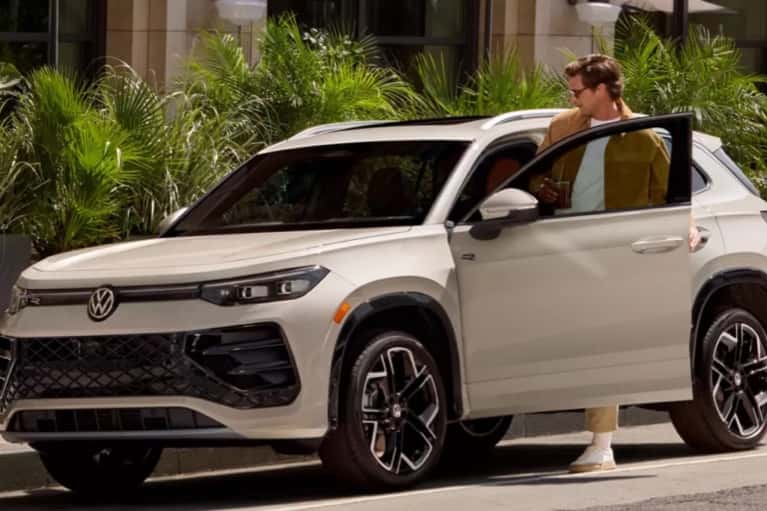 man entering 2025-VW-Tiguan-parked-on-city-street