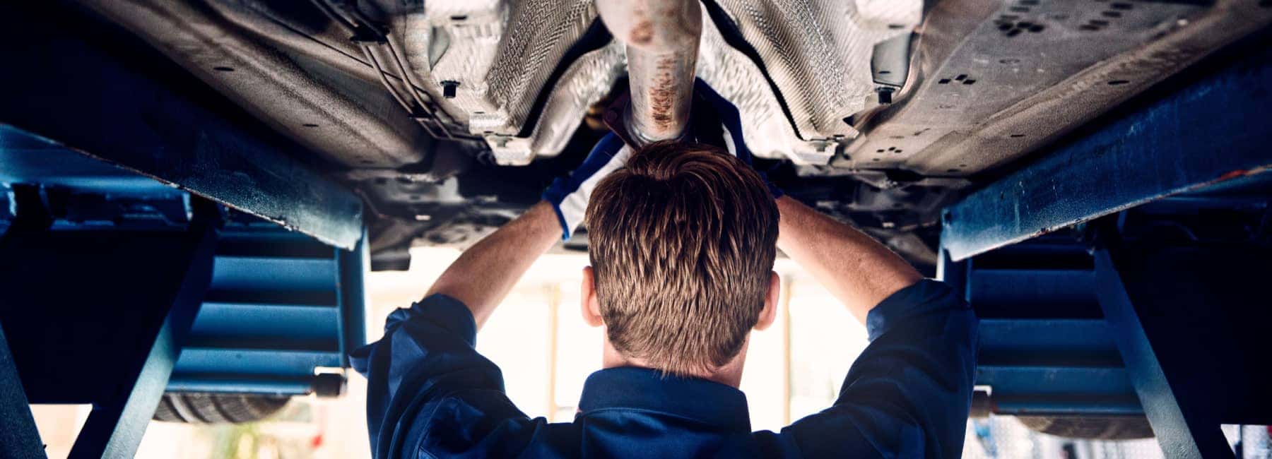 Volvo Service Technician working on the underside of a vehicle