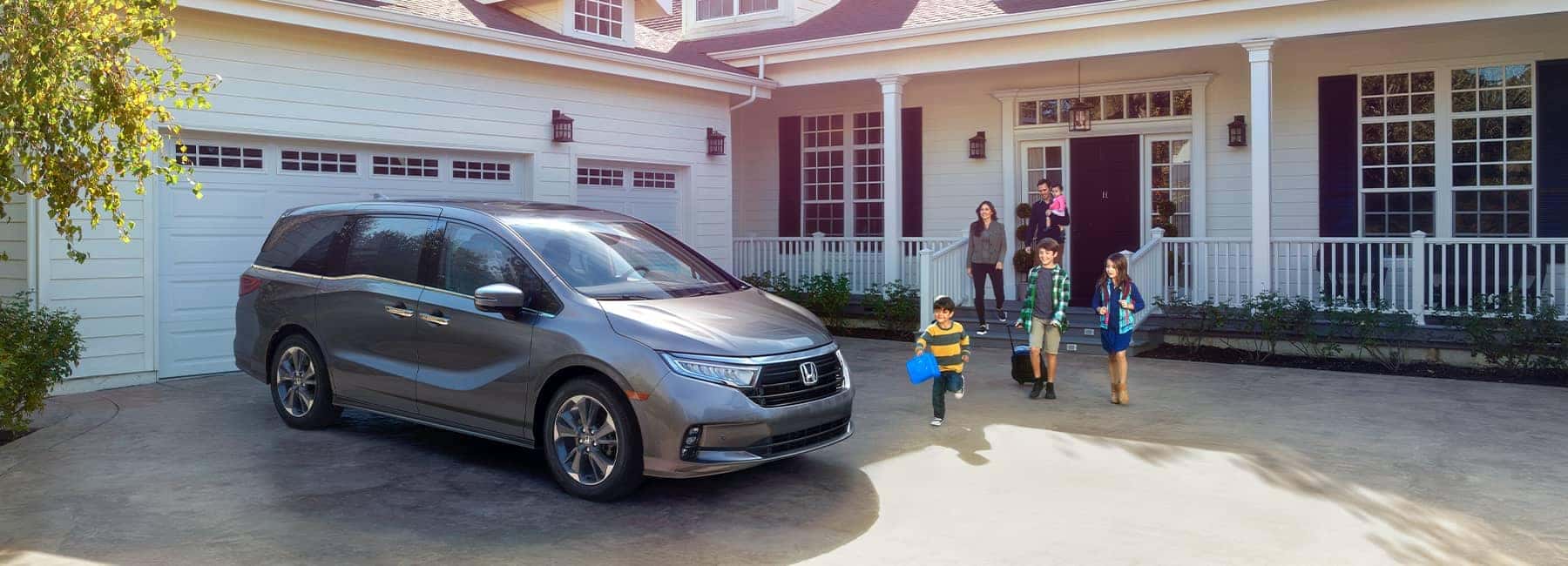 2021 Silver Honda Odyssey parked in front of a white home with black shutters