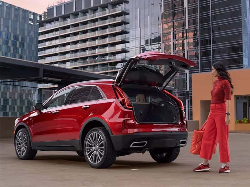 women in red with back open trunk Cadillac