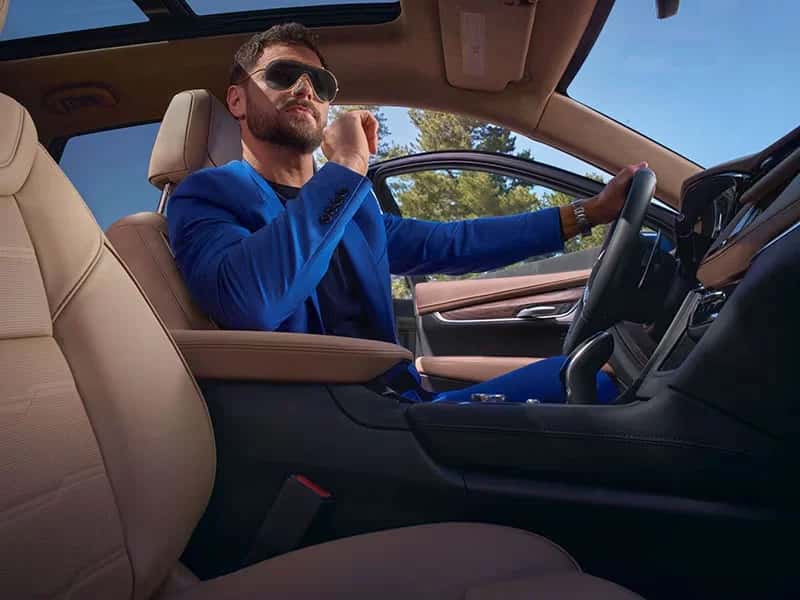 man in blue suit sits in Cadillac