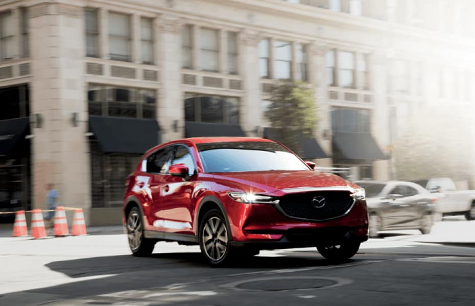 A red Mazda sedan is turning city corner