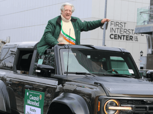 A person in a green jacket standing in a black truck