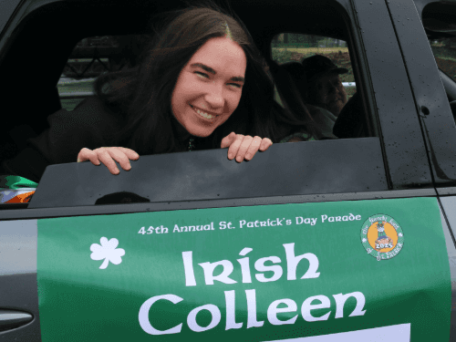 A person smiling in a car with a sign