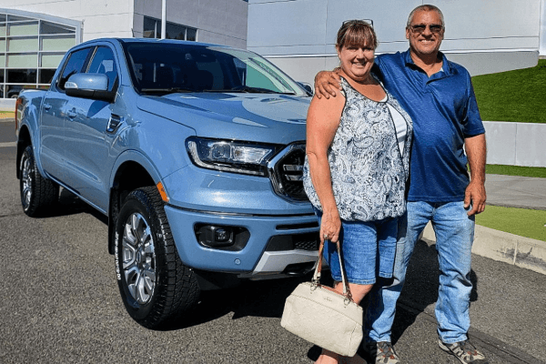 A person and person standing next to a blue truck