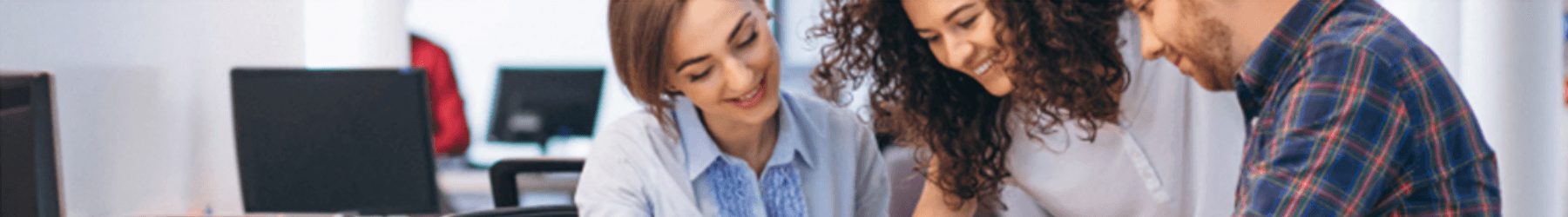 Man and two women in an office setting pointing and signing auto loan documents.