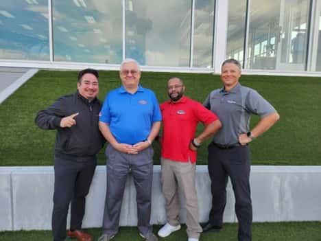 A group of men standing in front of a green wall