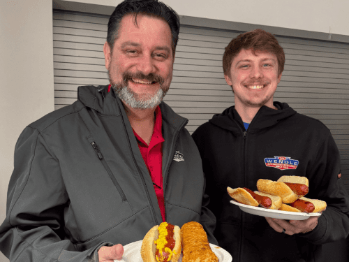 Two men holding plates of hot dogs
