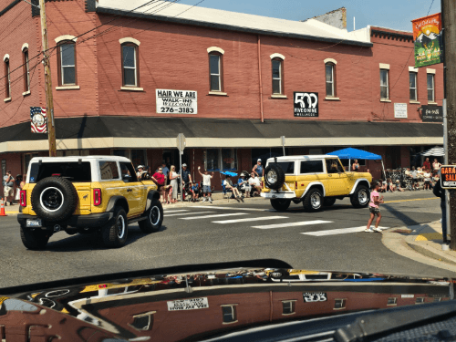 Two yellow cars driving on a street