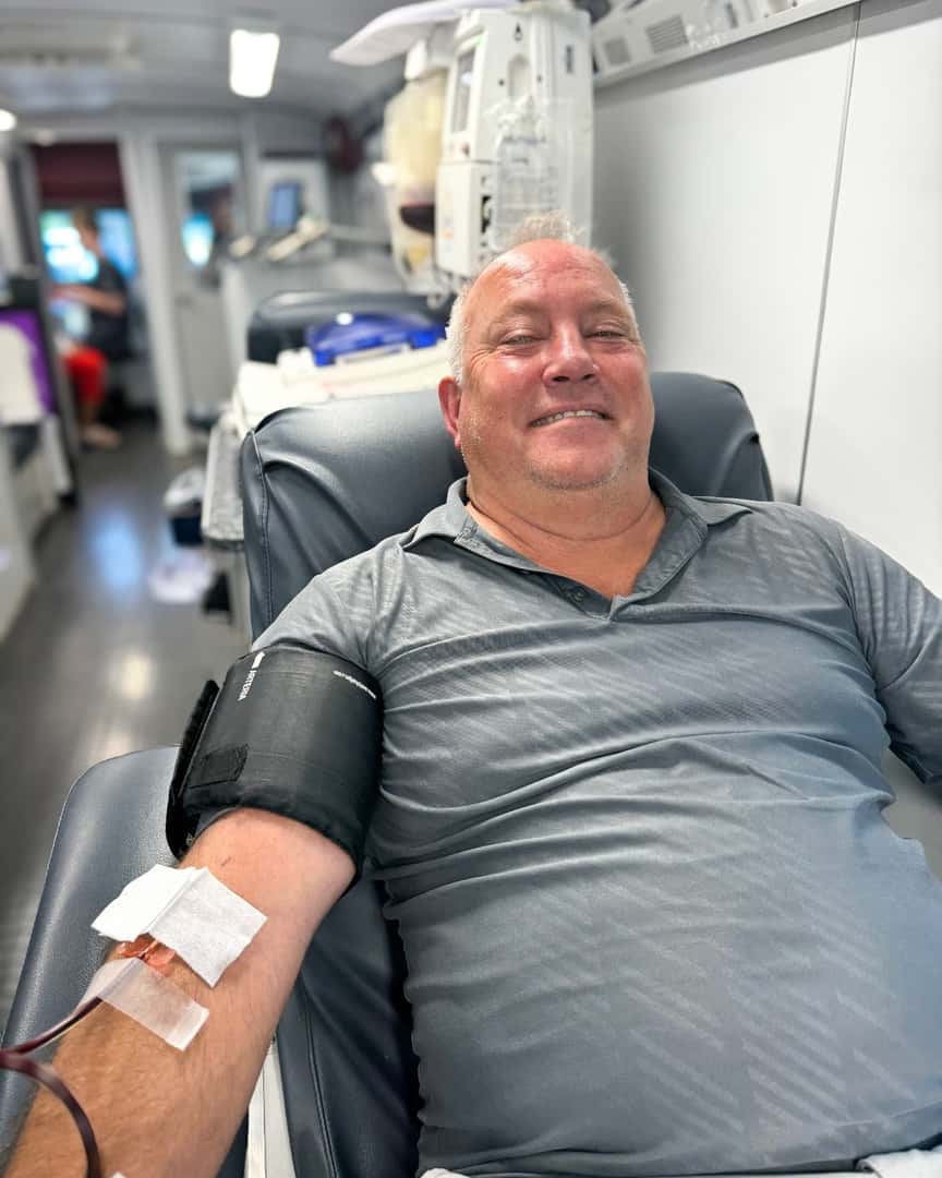 A person lying in a chair with a blood transfusion