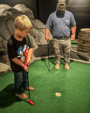 A person and child playing mini golf