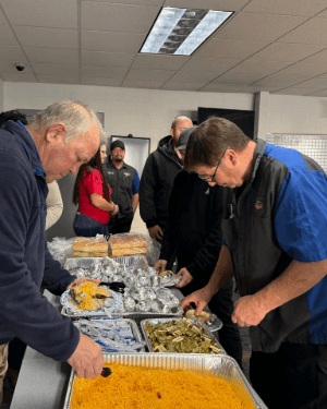 A group of people standing around a table full of food