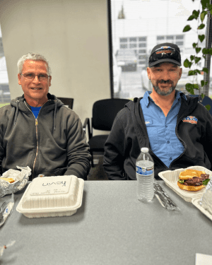 Two men sitting at a table with food