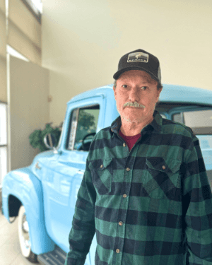 A person standing in front of a blue truck