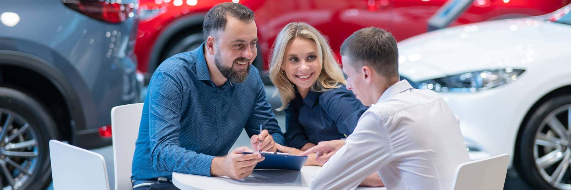 Two people in a dealership showroom sitting with a finance advisor