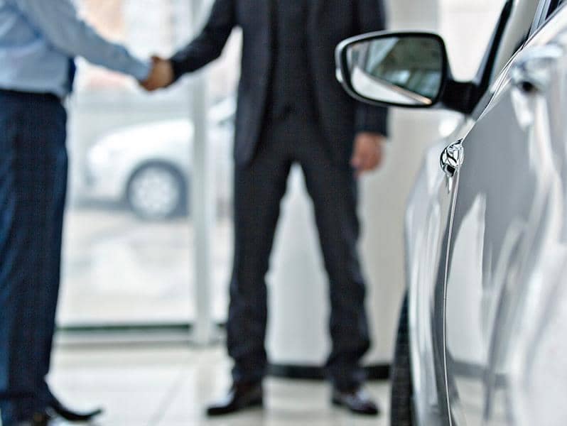 A customer shakes hands with the salesman after returning his leased silver Buick