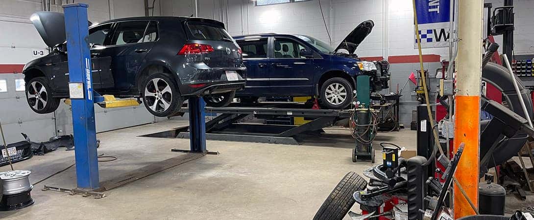 two cars up on jacks in auto body shop
