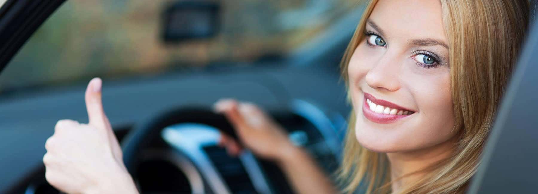 smiling-woman-in-car-gives-thumbs-up